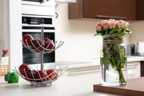 a vase of flowers and a bowl of apples on a kitchen counter at Forest Park Garden Apartment in Bratislava