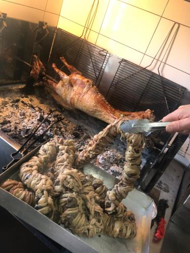 a person is cooking food on a grill at Hotel Ambassador Voskopojë in Voskopojë