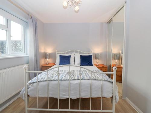 a bedroom with a white bed with blue pillows at The Beach House in Pwllheli