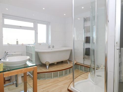 a white bathroom with a tub and a sink at The Beach House in Pwllheli