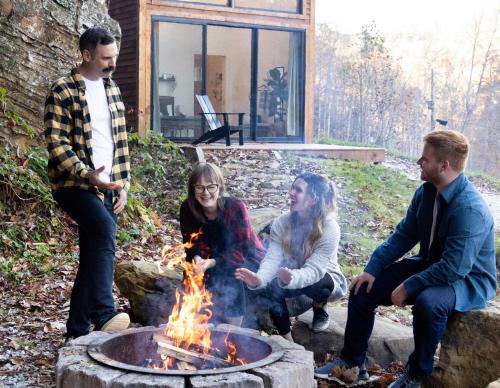 four people sitting around a fire pit at Tiny Cabin in RRG - The Naturalist in Rogers