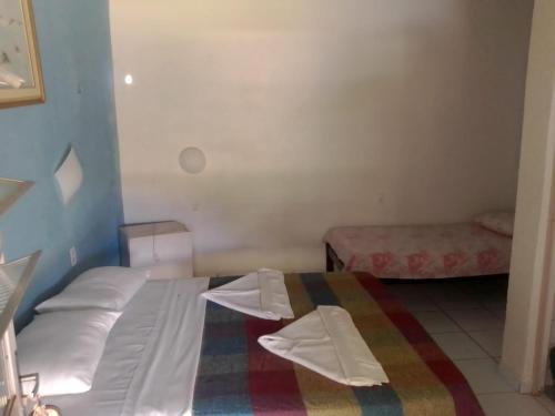 Pousada Elpirata Sidney في Ceará-Mirim: غرفة نوم بسرير مع شراشف بيضاء وبطانية