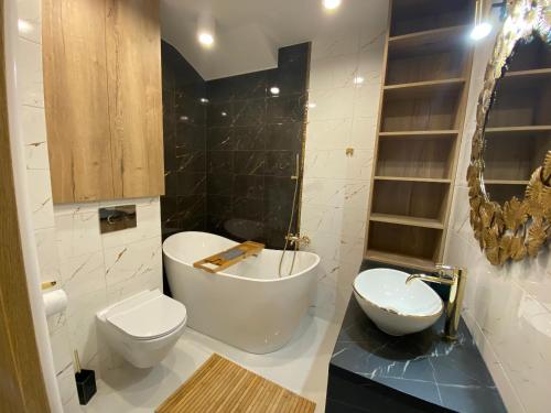 a bathroom with a tub and a toilet and a sink at Apartament na Spokojnej 24J/16 in Wisła