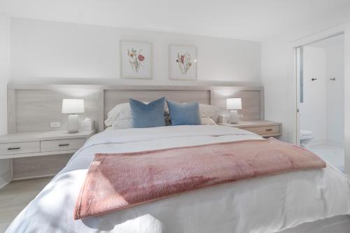 a white bedroom with a large bed with blue pillows at The Rest at Potomac Farms in Ashburn