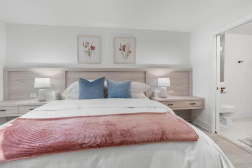 a white bedroom with a large bed with blue pillows at The Rest at Potomac Farms in Ashburn