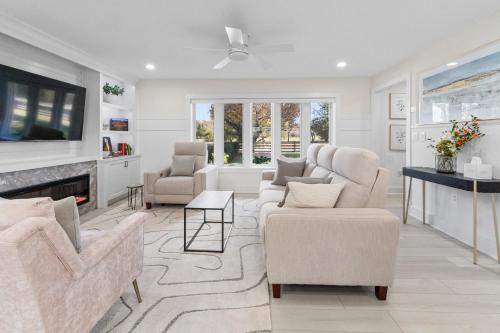 a living room with white furniture and a tv at The Rest at Potomac Farms in Ashburn