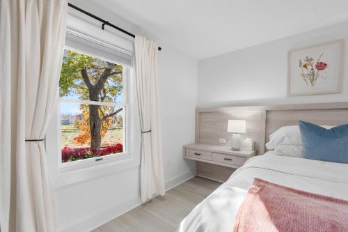 a bedroom with a bed and a window with a tree at The Rest at Potomac Farms in Ashburn