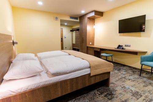 Dormitorio con cama, escritorio y TV en Spa & Wellness Hotel Fitak**** en Liptovský Ján