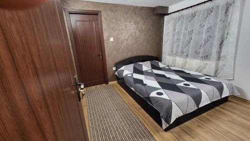 a bedroom with a bed with a black and white comforter at Casa D in Topliţa