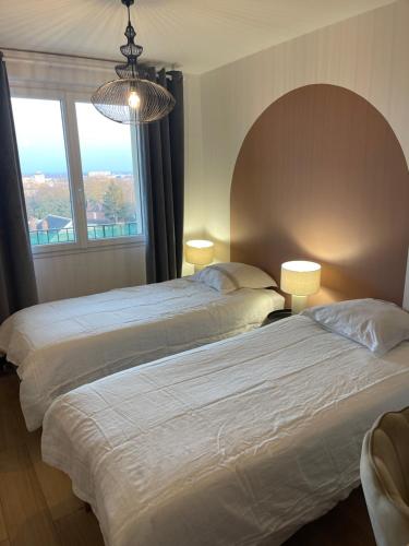 Duas camas num quarto com uma grande janela. em Les Chambres de Troyes - Parking Free Fibre Netflix em Troyes