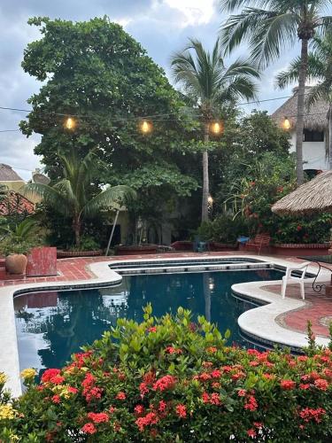 a swimming pool in a resort with flowers and trees at Casa Limon in Puerto Escondido