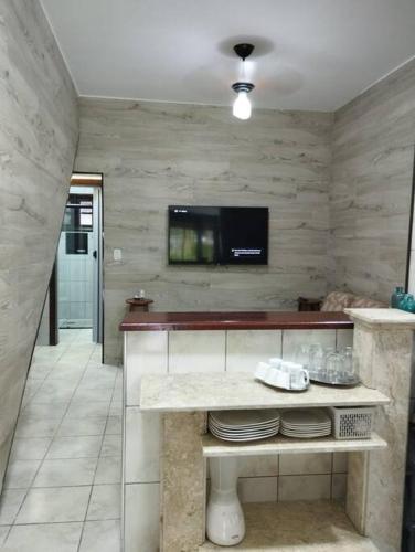 a kitchen with a table with a tv on the wall at Apê Aconchegante - 4 pessoas in Bertioga