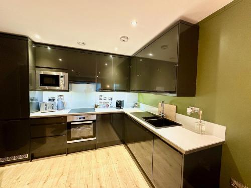 une cuisine avec des armoires noires et un comptoir blanc dans l'établissement The Stag City Centre Cosy 1 Bed Long Term Stays Welcome, à Plymouth