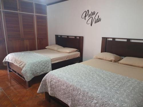 1 dormitorio con 2 camas y un cartel en la pared en BORUKA BnB, en Alajuela