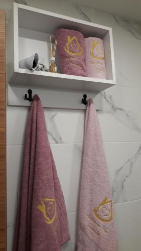 Baño con toallas rosas colgadas en la pared en Apartman NEDA Zlatibor, en Zlatibor