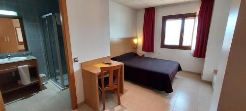 Habitación pequeña con cama y baño. en Hotel Font del Pla en La Jonquera