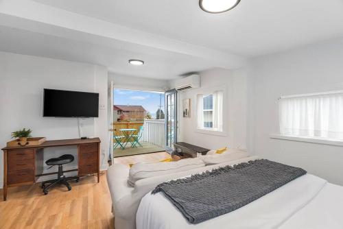 a white bedroom with a bed and a desk and a television at Walk to the waterfront! The Hobbit House in Tacoma