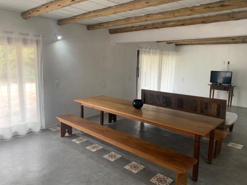 a wooden table and bench in a room with a television at Casa Flor da Terra in Caraíva