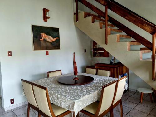 a dining room with a table and chairs and stairs at LARA'S HOUSE in São Sebastião