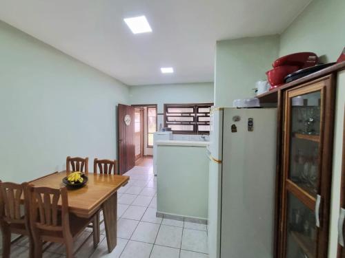 a kitchen with a table and a white refrigerator at LARA'S HOUSE in São Sebastião