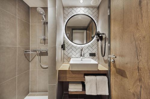 een badkamer met een wastafel en een spiegel bij H2 Hotel Mainz in Mainz