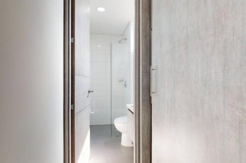 a bathroom with a toilet and a glass door at Inigualable Loft en el norte. in Bogotá