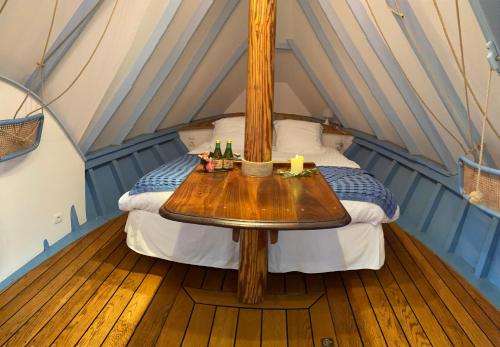 uma cama numa tenda com uma mesa de madeira em LA CALOGE KASTELL DINN em Crozon