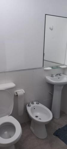 a white bathroom with a toilet and a sink at El Refugio in San Fernando del Valle de Catamarca