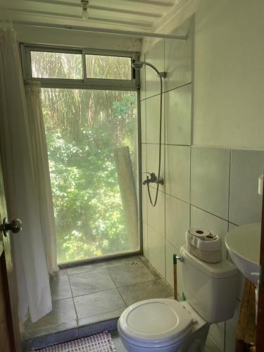 baño con aseo y lavabo y ventana en Nahele Lodge, en Santa Teresa Beach