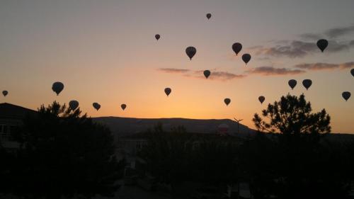 un grupo de globos de aire caliente en el cielo al atardecer en Hotel Ozyel, en Ortahisar