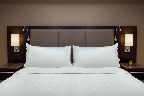 a large bed with white pillows and two night stands at Holiday Inn and Suites Phoenix Airport North by IHG in Phoenix