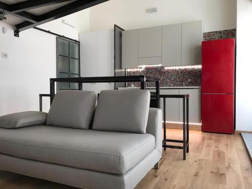 a living room with a couch and a red kitchen at Loft -MM Piazza Bande Nere in Milan