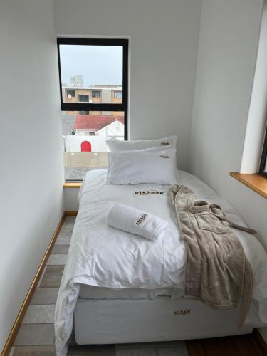 białe łóżko w pokoju z oknem w obiekcie Top Floor Executive apartment w Kapsztadzie