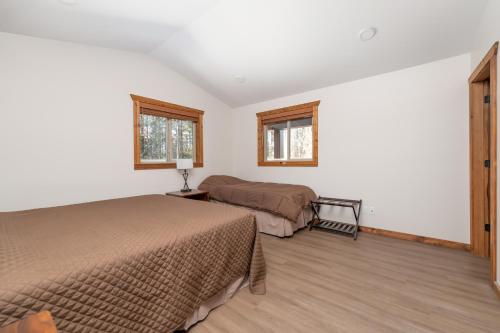 1 dormitorio con 2 camas y 2 ventanas en The Evergreen Cabin, en Valemount