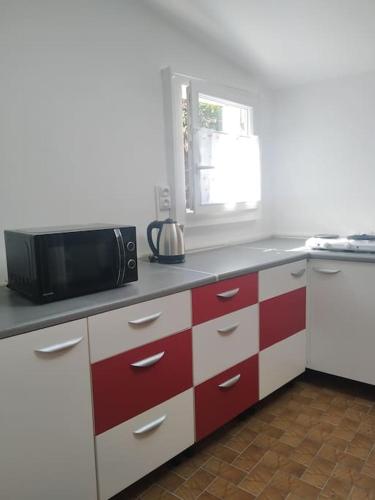 a kitchen with red and white cabinets and a microwave at Ty Gwenn la veritable Bretagne in Plésidy