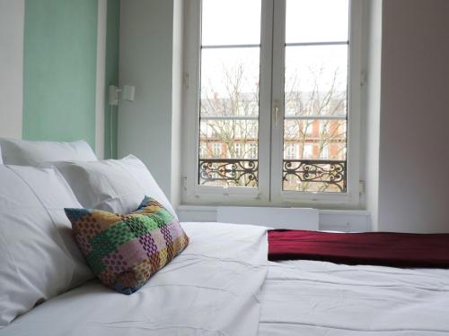 une chambre avec un lit blanc avec une fenêtre dans l'établissement Strasbourg Evasion Pop, à Strasbourg