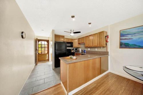 a kitchen with wooden cabinets and a black refrigerator at Kauai Banyan Harbor B24 condo in Lihue