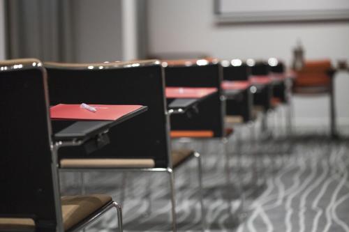 a row of black chairs with red desks in a room at Hotel Rafael in Milan