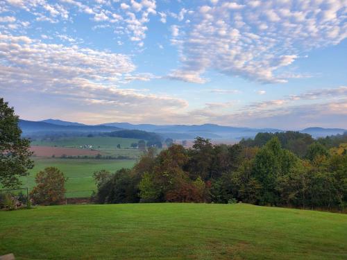 a green field with trees and a cloudy sky at The Loft at Hebron Valley Overlook in Madison