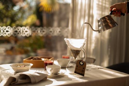 a person is pouring coffee into a table with a lamp at Hotel Muchele in Postal