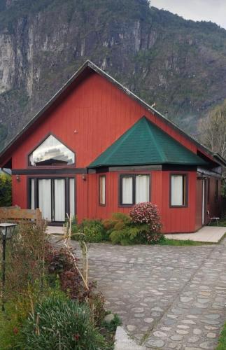 una casa roja con techo verde y montaña en La casona de Llifen, en llifen