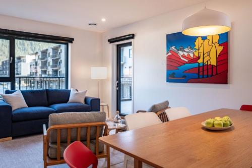 a living room with a table and a blue couch at Hygge Haus by Revelstoke Vacations in Revelstoke