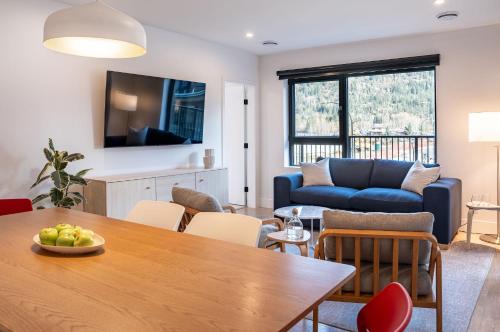 a living room with a table and a blue couch at Hygge Haus by Revelstoke Vacations in Revelstoke