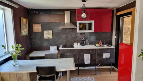 una cocina con armarios rojos y una mesa con sillas. en Típica Casa de Piedra, en Santiago de Compostela