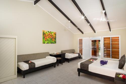 a hotel room with two beds and a table and chairs at Plantation Island Resort in Malolo Lailai