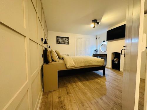a bedroom with a bed and a wooden floor at The Nook Cottage, Parkgate, Wirral in Parkgate