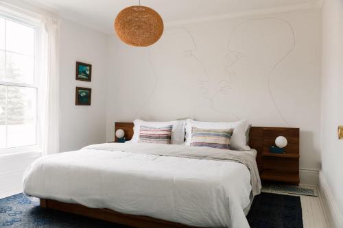 a white bedroom with a large bed with pillows at Town & Trail - Walkable Wellington Charmer in Wellington