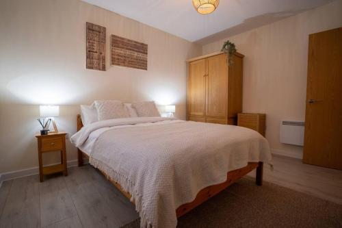 Cosy 2 Bedroom flat in Stevenage في ستيفنيج: غرفة نوم بسرير كبير وخزانة خشبية