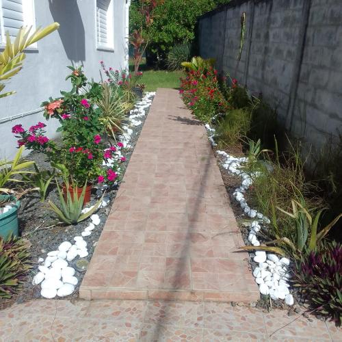 a garden with a brick walkway and flowers at Maison verte in Capesterre-Belle-Eau
