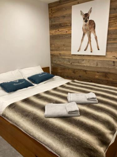 a bed with two pillows and a picture of a deer at 1650 Moriond - 2 Double Bedroom near Snow Front in Courchevel